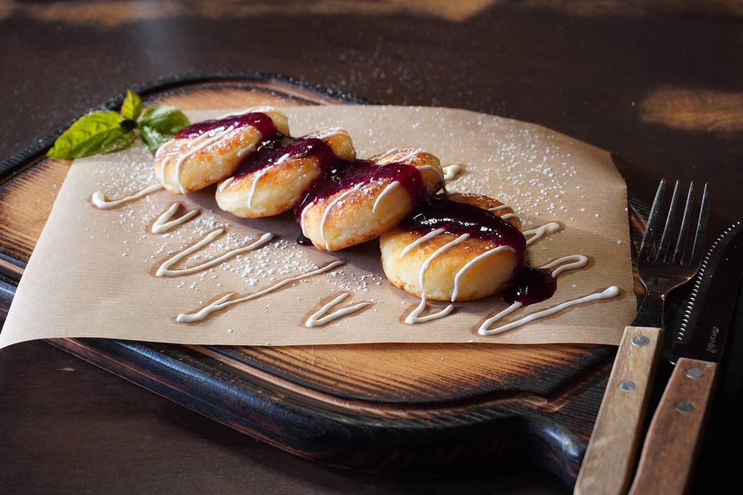 Сирнички з вишневим соусом та згущенкою